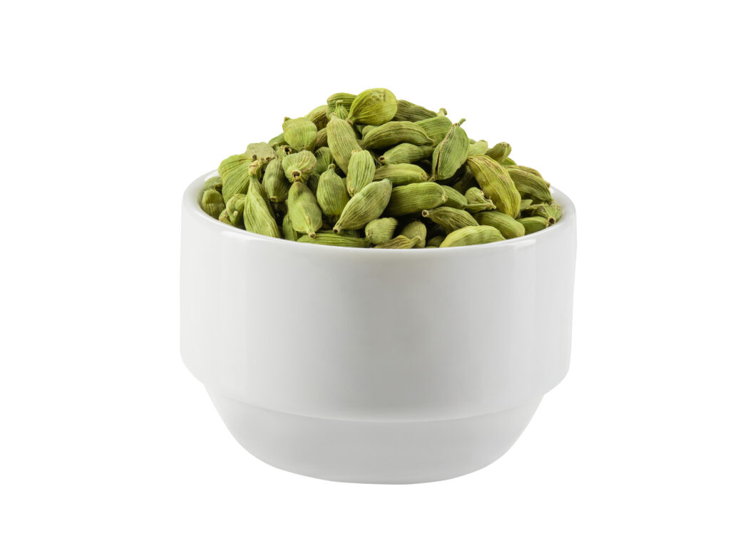 Green cardamom pods in a bowl isolated on white background with copy space for text or images. Spices, food, cooking concept. Close-up shot.